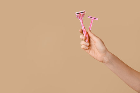 Female hand with razors on brown backgroundの写真素材