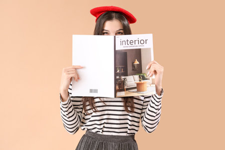 Young woman with magazine on beige backgroundの写真素材