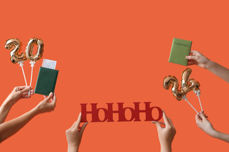 Female hands holding passports with Christmas decor on orange background. New year vacation concept