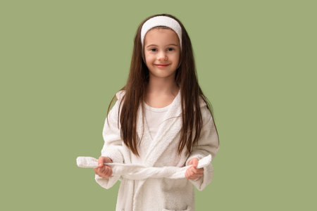 Cute little happy girl in bathrobe on green backgroundの写真素材