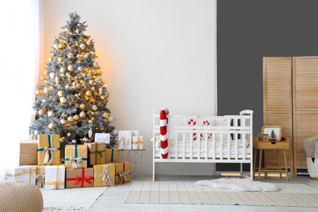 Interior of light bedroom with baby crib, Christmas tree and presentsの写真素材