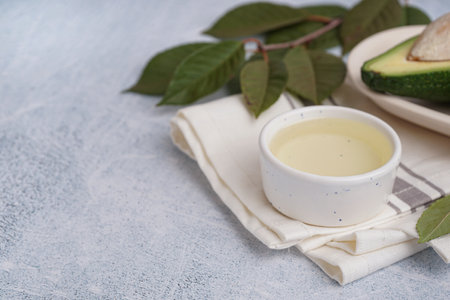 Bowl of essential oil with napkin and leaves on grunge gray backgroundの写真素材