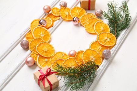 Frame made of dried orange slices with fir branches, Christmas balls and gift boxes on white backgroundの写真素材