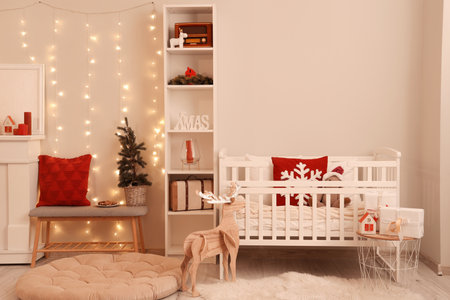 Interior of bedroom with baby crib, Christmas tree and glowing lights in eveningの写真素材