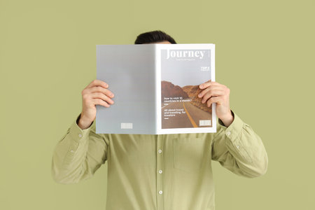 Handsome man reading magazine on green backgroundの写真素材