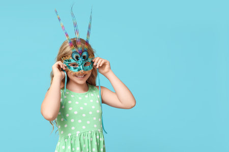 Pretty little girl wearing carnival mask on blue backgroundの写真素材