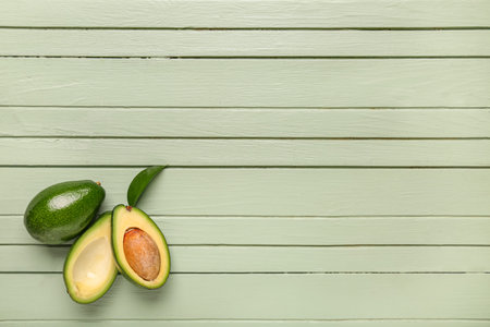 Fresh ripe avocados and leaf on green wooden background