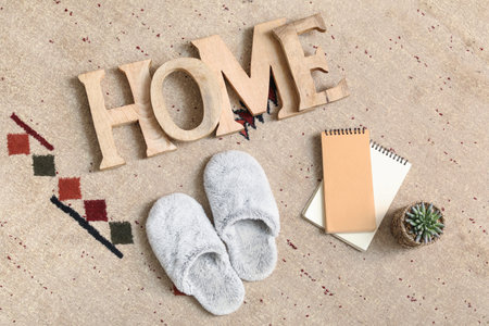 Soft slippers with word HOME and notebooks on carpet, top viewの写真素材