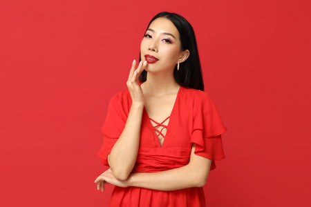 Beautiful Asian woman with stylish makeup on red backgroundの写真素材