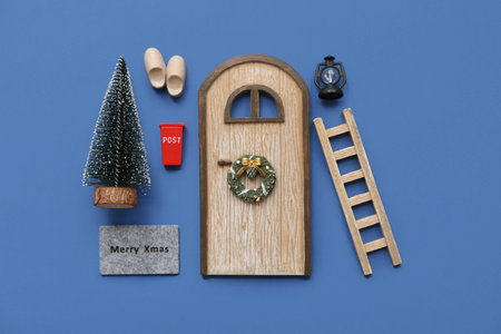 Beautiful composition with door, ladder, Christmas tree and decorations on blue background