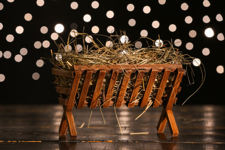 Manger with hay on table against blurred lights. Concept of Christmas storyの写真素材