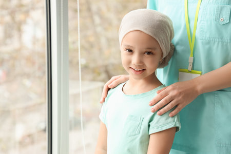 Little Asian girl after chemotherapy with nurse in clinic, closeupの写真素材