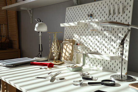 Stylish accessories with tools on table of jeweler in workshop