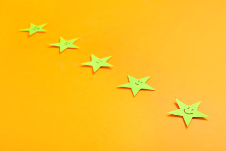Rating stars with smiles on orange background, closeup. Customer experience conceptの写真素材
