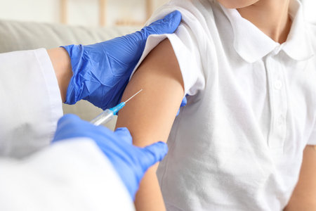 Ill little boy with doctor vaccinating at home, closeupの写真素材