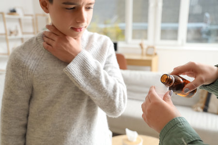 Mother pouring cough syrup for her sick little son at home, closeupの写真素材