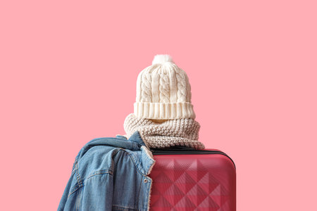 Suitcase with warm clothes on pink background. Winter vacation conceptの写真素材