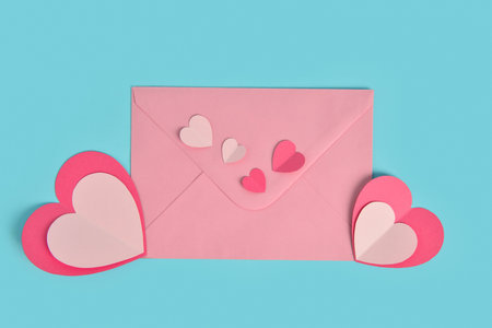 Envelope with paper hearts on blue background