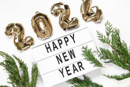 Board with text HAPPY NEW YEAR , figure 2024 made of foil balloons and thuja branches on white background, closeupの写真素材