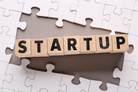 Cubes with word STARTUP and puzzle pieces on gray background