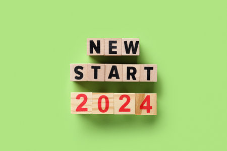 Wooden cubes with text NEW START 2024 on green backgroundの写真素材