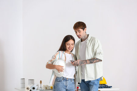 Young couple using mobile phone during repair in their new houseの写真素材