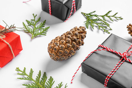 Pine cone with coniferous branches and Christmas gift boxes on white background