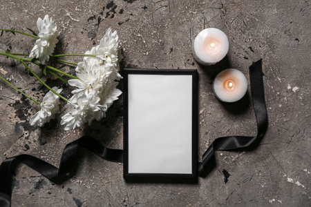 Blank funeral frame, black, ribbon, flowers and burning candles on grunge backgroundの写真素材