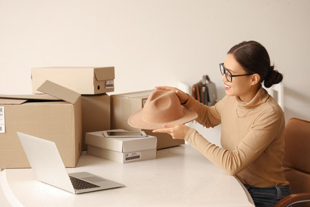 Young Asian woman selling hat online in warehouse storeの写真素材