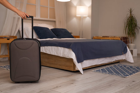 Female guest with suitcase in hotel roomの写真素材