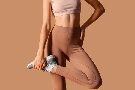 Sporty young woman in leggings on beige backgroundの写真素材