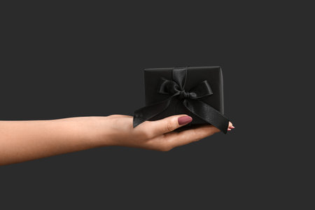 Female hand with gift box on dark background. Black Fridayの写真素材