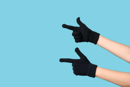 Hands in warm gloves pointing at something on blue background