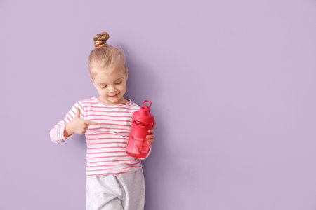 Cute little pointing at bottle of water near lilac wallの写真素材