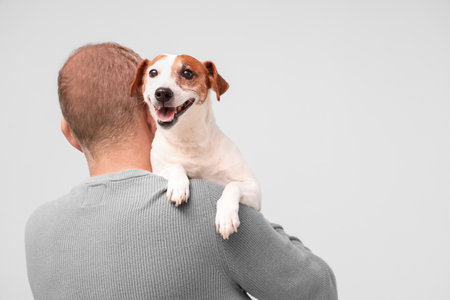 Senior man with cute dog on light blue backgroundの写真素材