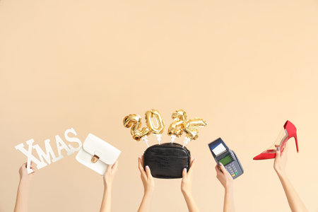 Female hands with payment terminal, bags and Christmas decor on beige background. New year shopping...