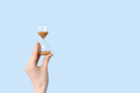 Female hand holding hourglass on blue background