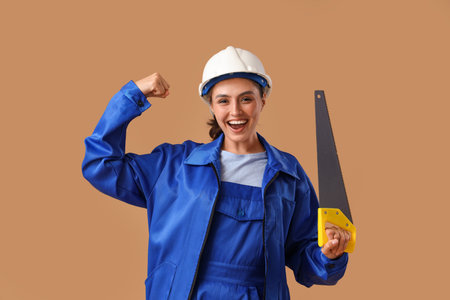 Happy female worker with handsaw on brown backgroundの写真素材