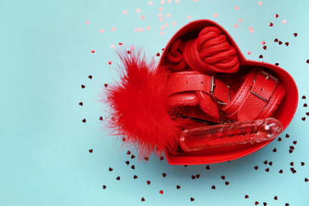 Gift box with different sex toys and heart shaped air balloons on blue background. Valentine's Day celebrationの写真素材