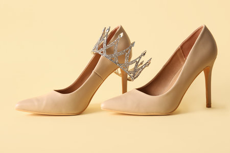 Stylish high-heeled shoes with crown on color backgroundの写真素材
