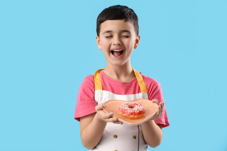 Cute little boy with donut on blue background. Valentine's Day celebrationの写真素材