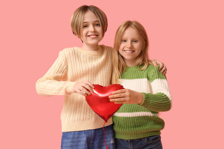 Little children with heart-shaped balloon on pink background. Valentine's Day celebrationの写真素材
