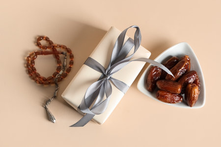 Gift box with prayer beads and dried dates for Ramadan on beige backgroundの写真素材