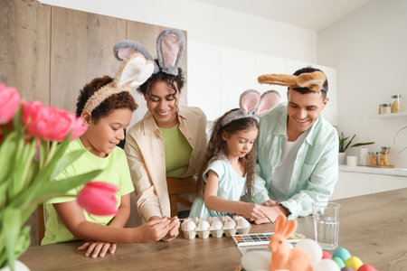Happy family painting eggs in kitchen on Easter Dayの写真素材