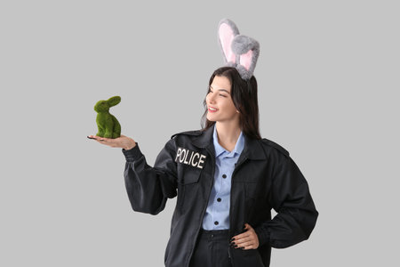 Female police officer in bunny ears with Easter rabbit on light backgroundの写真素材
