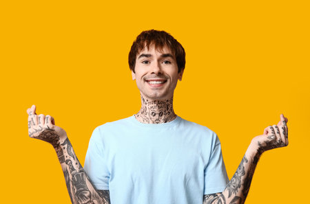 Handsome young man making hearts with fingers on yellow backgroundの写真素材