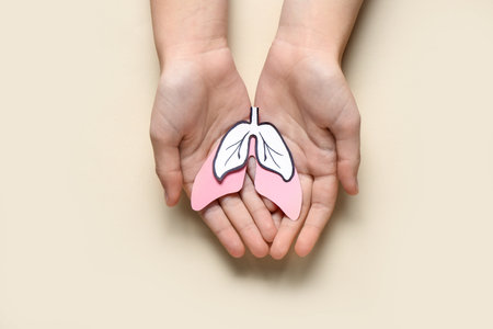 Female hands with paper lungs on beige backgroundの写真素材