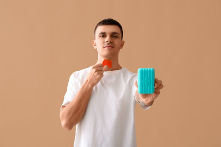 Young man with paper thyroid gland and pill box on beige backgroundの写真素材