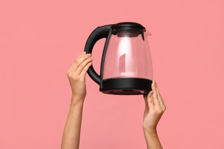Woman with electric kettle on pink backgroundの写真素材