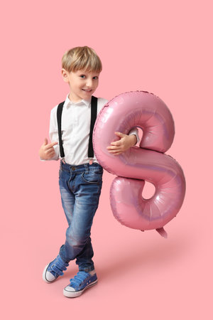 Cute little boy with air balloon in shape of figure 8 on pink background. International Women's Dayの写真素材